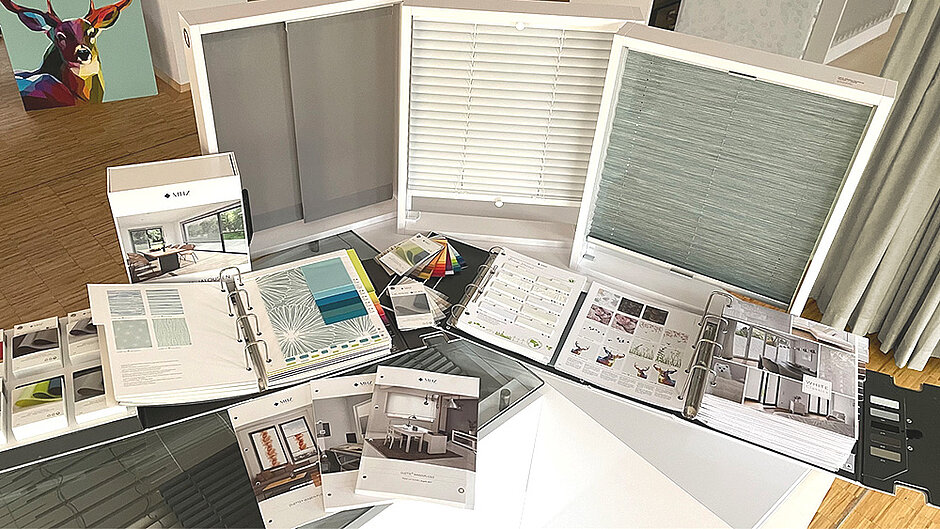 Table with MHZ sample collections, colour fans and information leaflets on sunshade products laid out on it