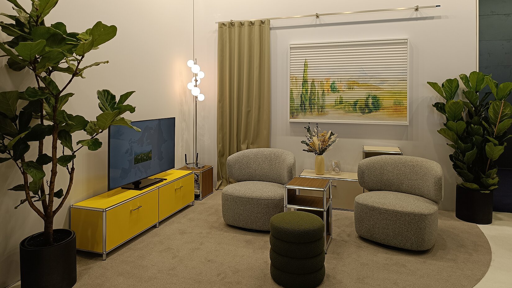 Modern eingerichtete Sitzecke mit Landschaftsplissee, Pflanzen, Sesseln und TV-Konsole am MHZ-Messestand.