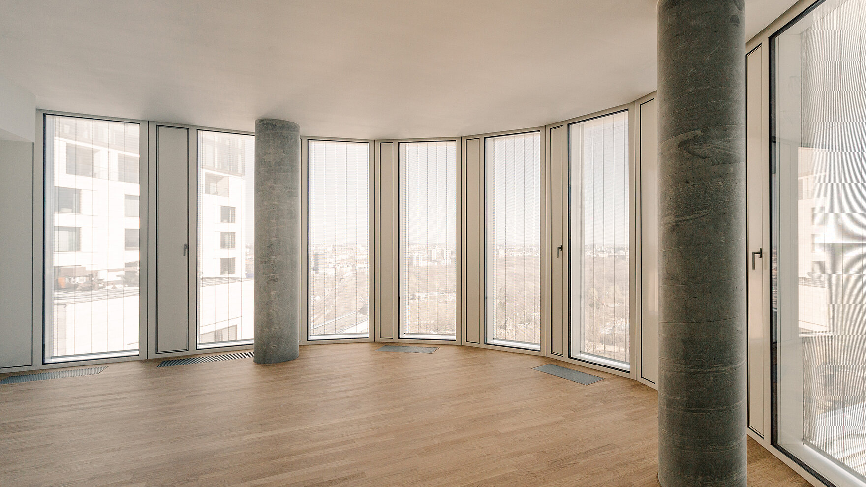 Interior with floor-to-ceiling windows and vertical MHZ metal blinds Senn facing a panoramic view.