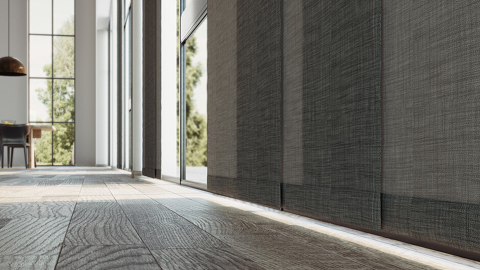 Nahaufnahme eines dunkel strukturierten Flächenvorhangs an einem großen Fenster mit sichtbarer Stofftextur und Schattenwurf.