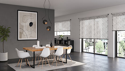 Urbanes Esszimmer mit floralen lichtdurchlässigen Rollos vor großen Fenstern. Blättermuster in feiner Struktur, helle Möbel und moderne Kunst an der Wand.