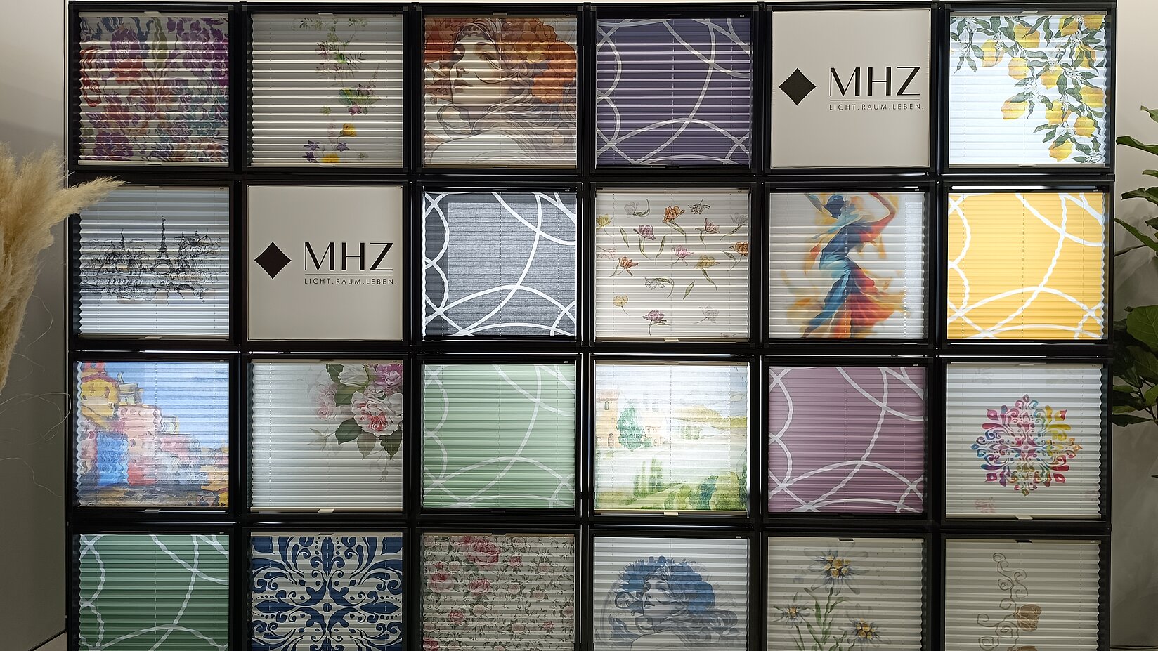 Plissee-Ausstellung mit MHZ-Logo und 20 unterschiedlich gestalteten Sichtschutzmustern auf einem modularen Messedisplay.
