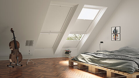 Schlafzimmer mit Dachschrägen und weißen Wabenplissees an zwei großen Dachfenstern.