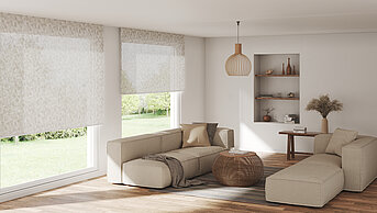 Wohnzimmer mit bodentiefen Fenstern und lichtdurchlässigen Rollos mit feinem Blättermuster. Naturfarbene Einrichtung, Holzakzente und sanftes Licht.