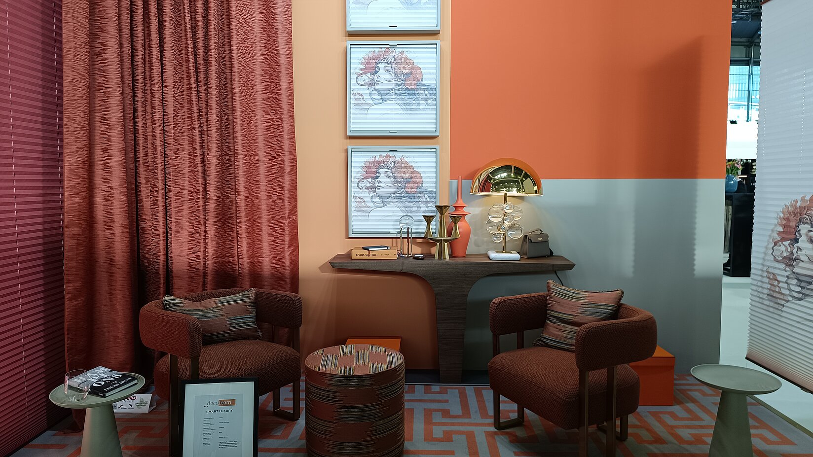 Stilvoller Messeraum mit orange-roten Möbeln, Wanddeko, Plissees mit Gesichtsmotiv und Vorhängen im decoteam-Stil.