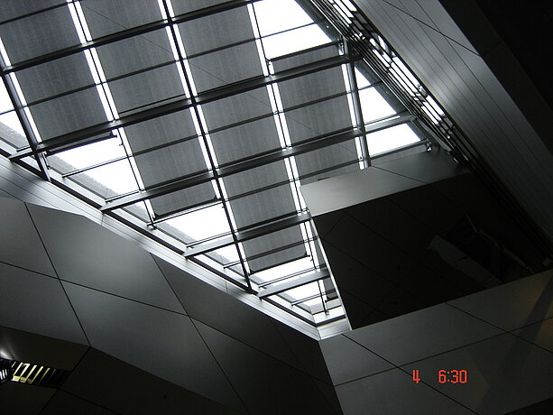 Innenansicht eines schrägen Glasdaches mit MHZ-Beschattungselementen in der BMW Welt, von unten fotografiert.