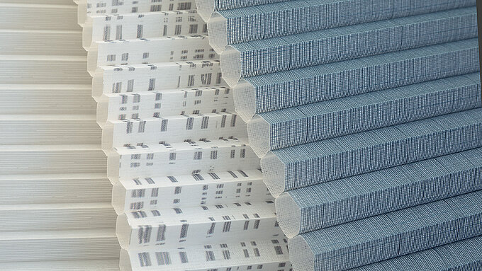 Verschiedene MHZ Wabenplissee-Stoffe in Nahaufnahme – mit grafischen Mustern und unterschiedlichen Gewebestrukturen.