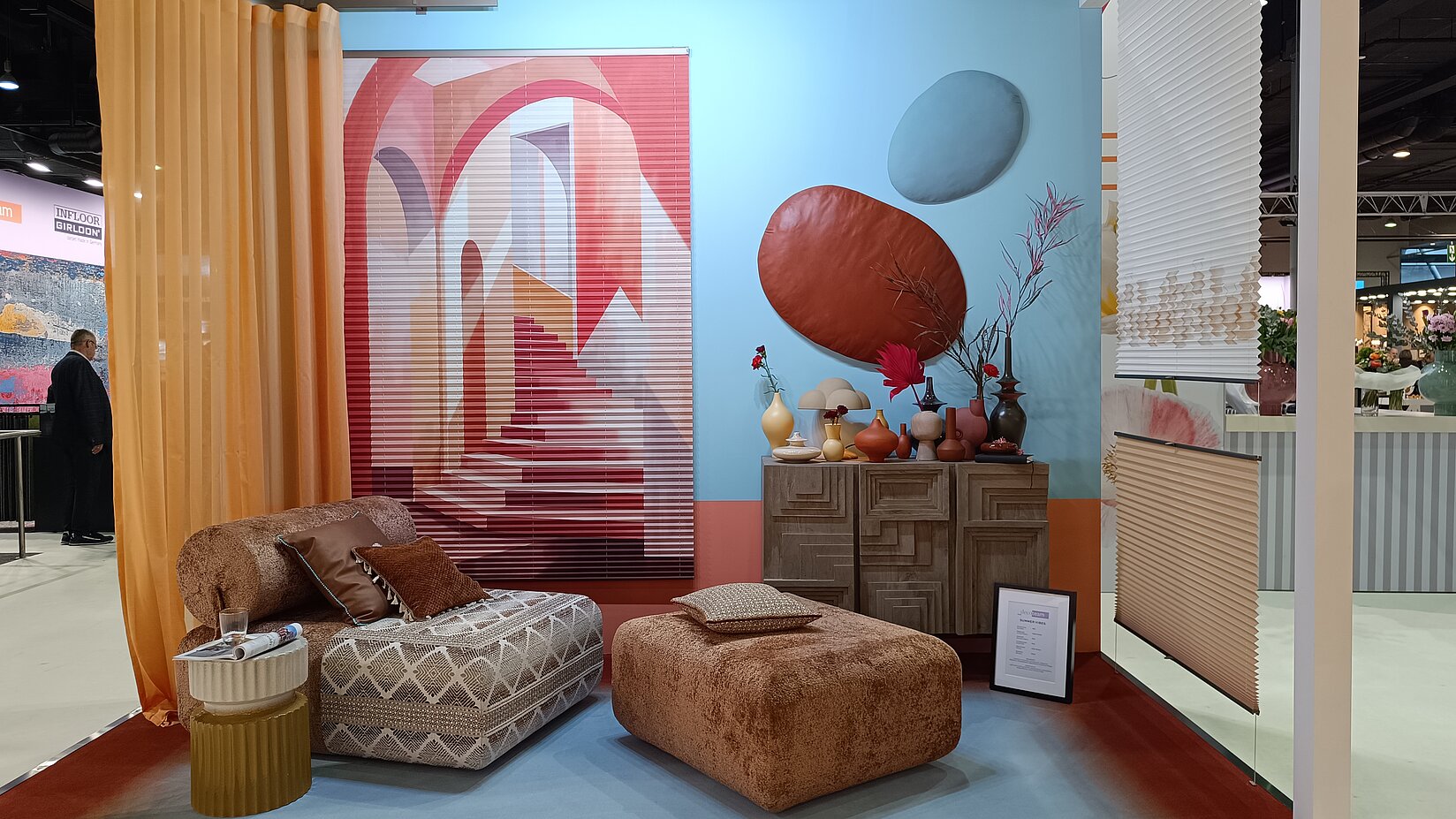 Messe-Wohnraum mit Vorhang- und Sonnenschutzsystemen sowie dekorativer Sitzecke.