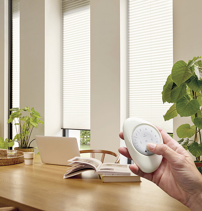 Smartphone mit PowerView-App und MHZ Pebble Funkhandsender zur Steuerung von Sicht- und Sonnenschutz.