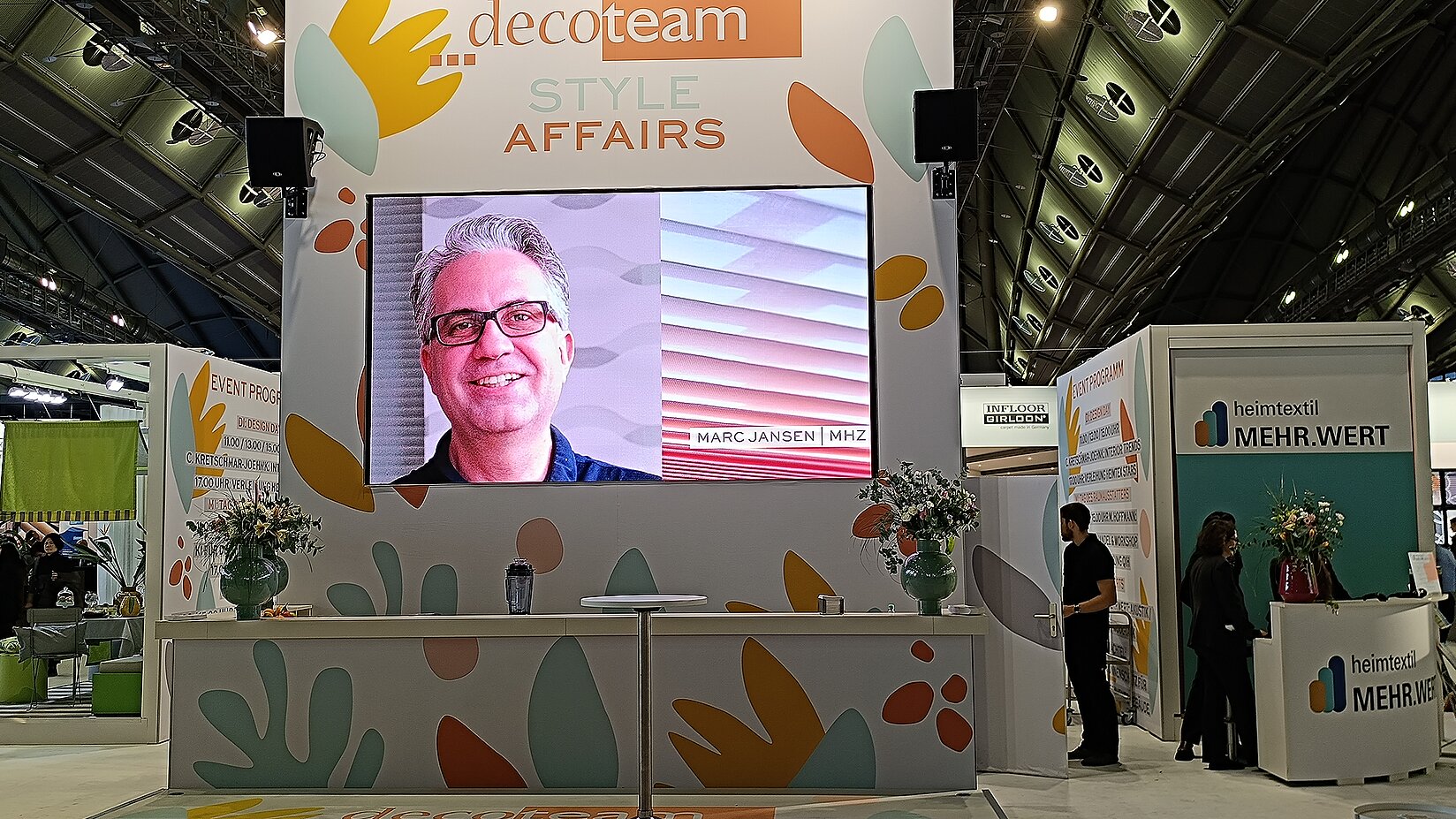 decoteam-Bühne auf der Heimtextil mit Großbildschirm, auf dem Marc Jansen (MHZ) zu sehen ist – Thema: Style Affairs.