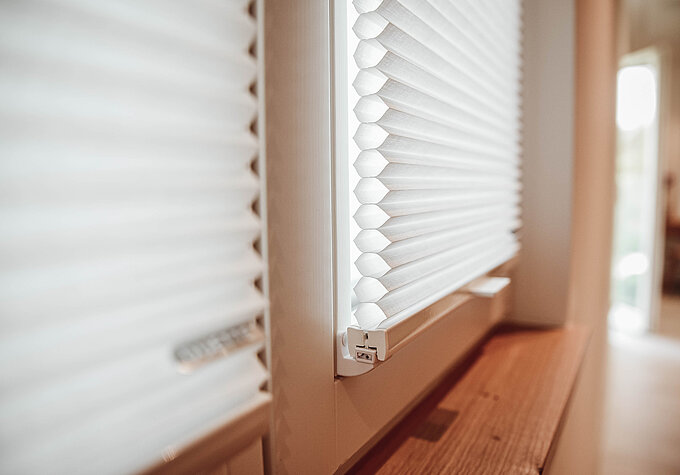 Nahaufnahme eines weißen Wabenplissees mit sichtbarer Zellstruktur, montiert im Fensterrahmen